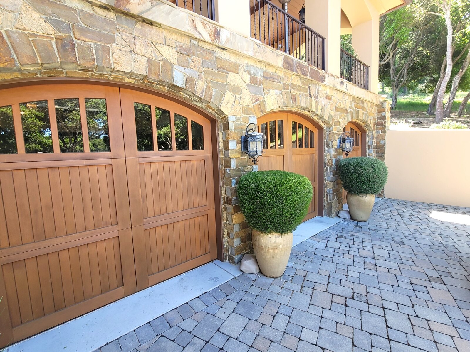 Wood carriage garage doors on a stone estate with paver driveway