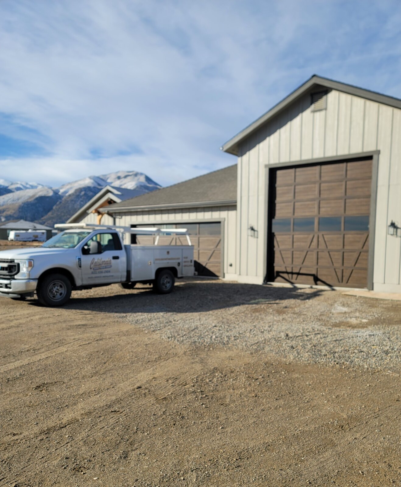 Wood-look commercial overhead door on a metal building with service truck