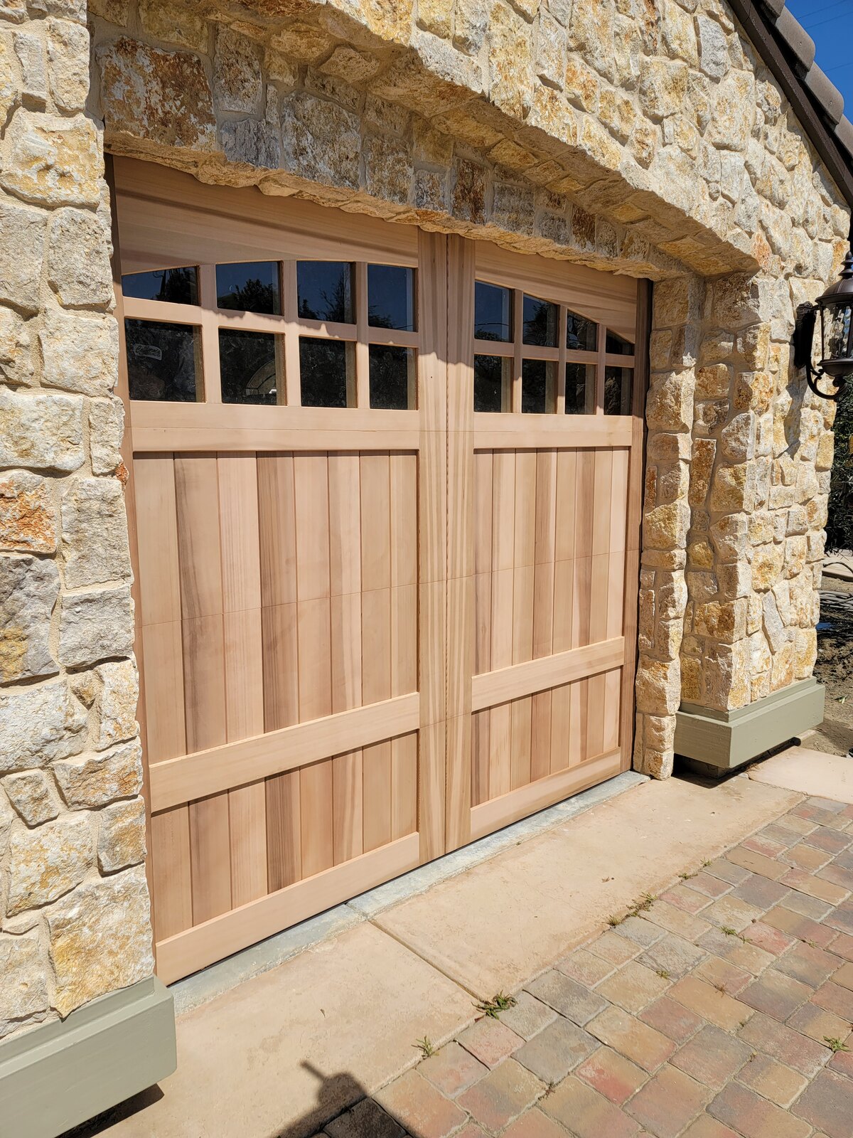 Custom real-wood carriage garage door with arched glass