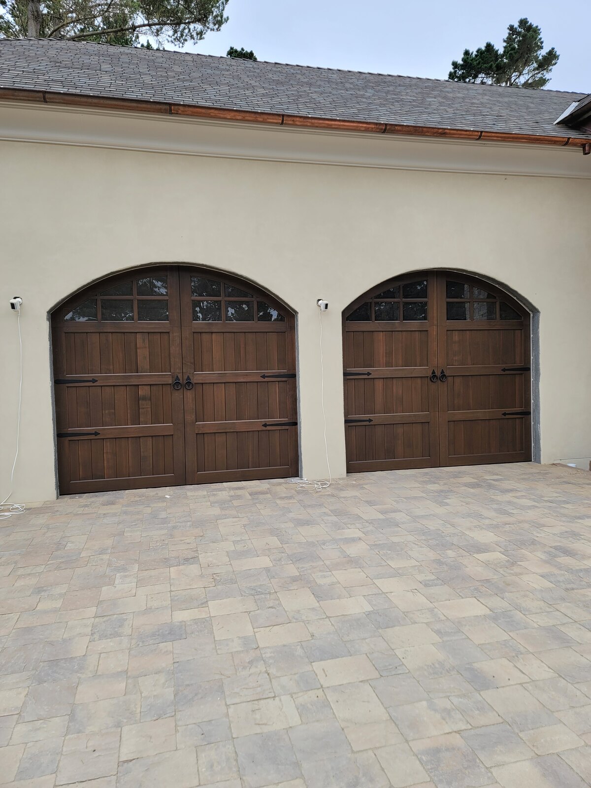 Wood-look carriage garage doors with arched windows on a stucco home