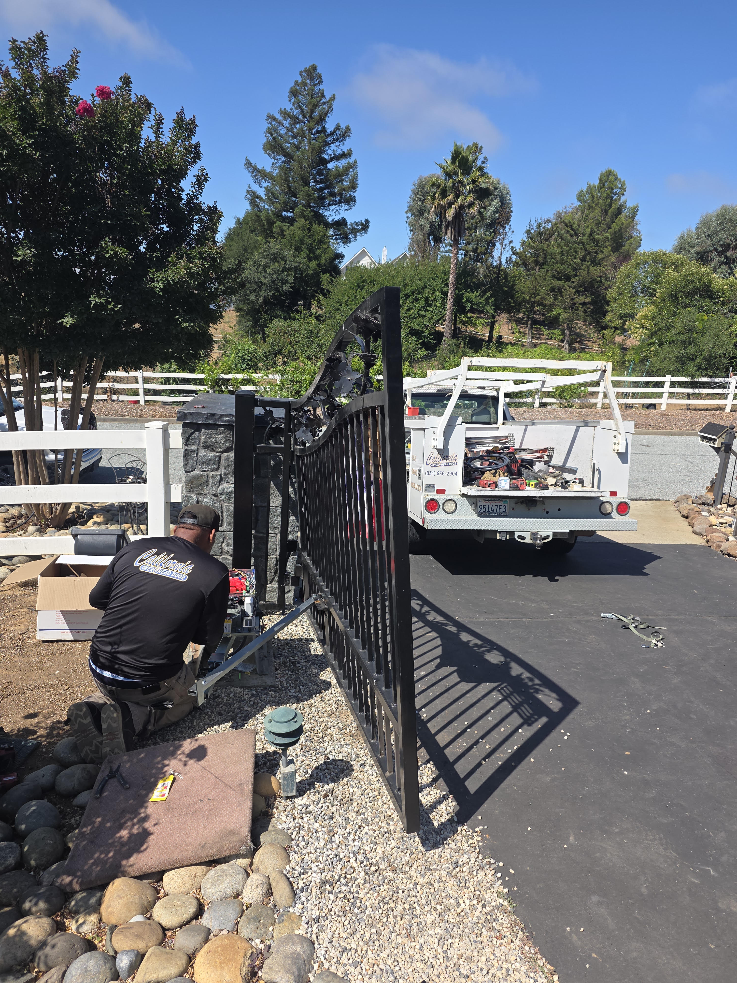 California Overhead Door technician installing an automatic gate opener on an ornamental iron driveway gate