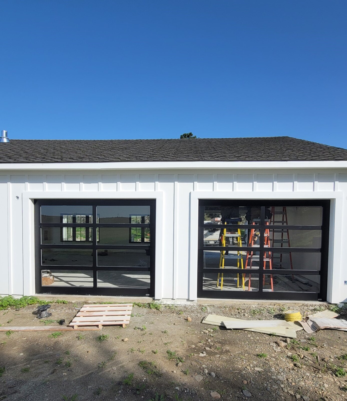 Full-view glass garage door on a modern farmhouse under construction