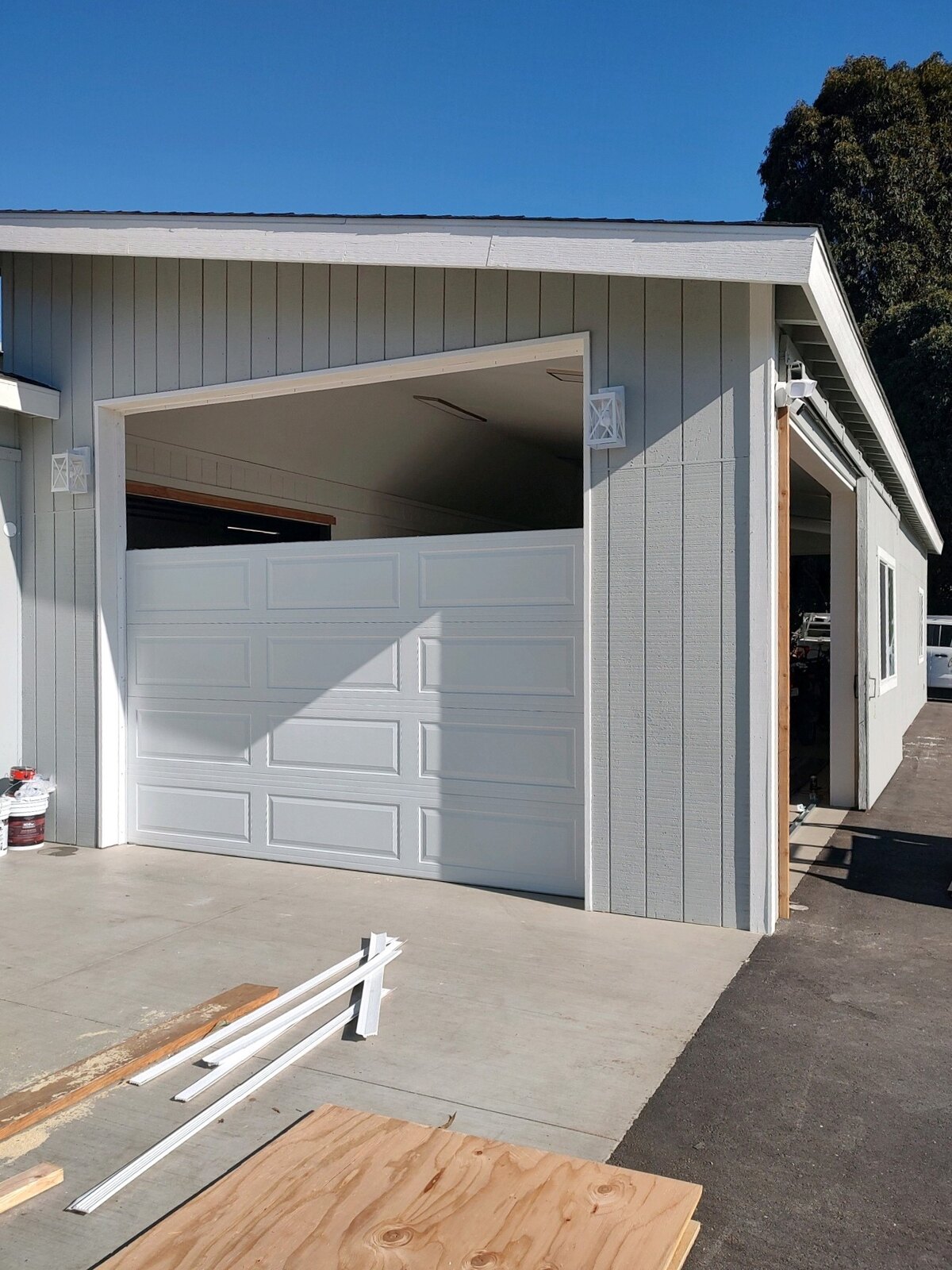 White sectional garage door on a board-and-batten outbuilding