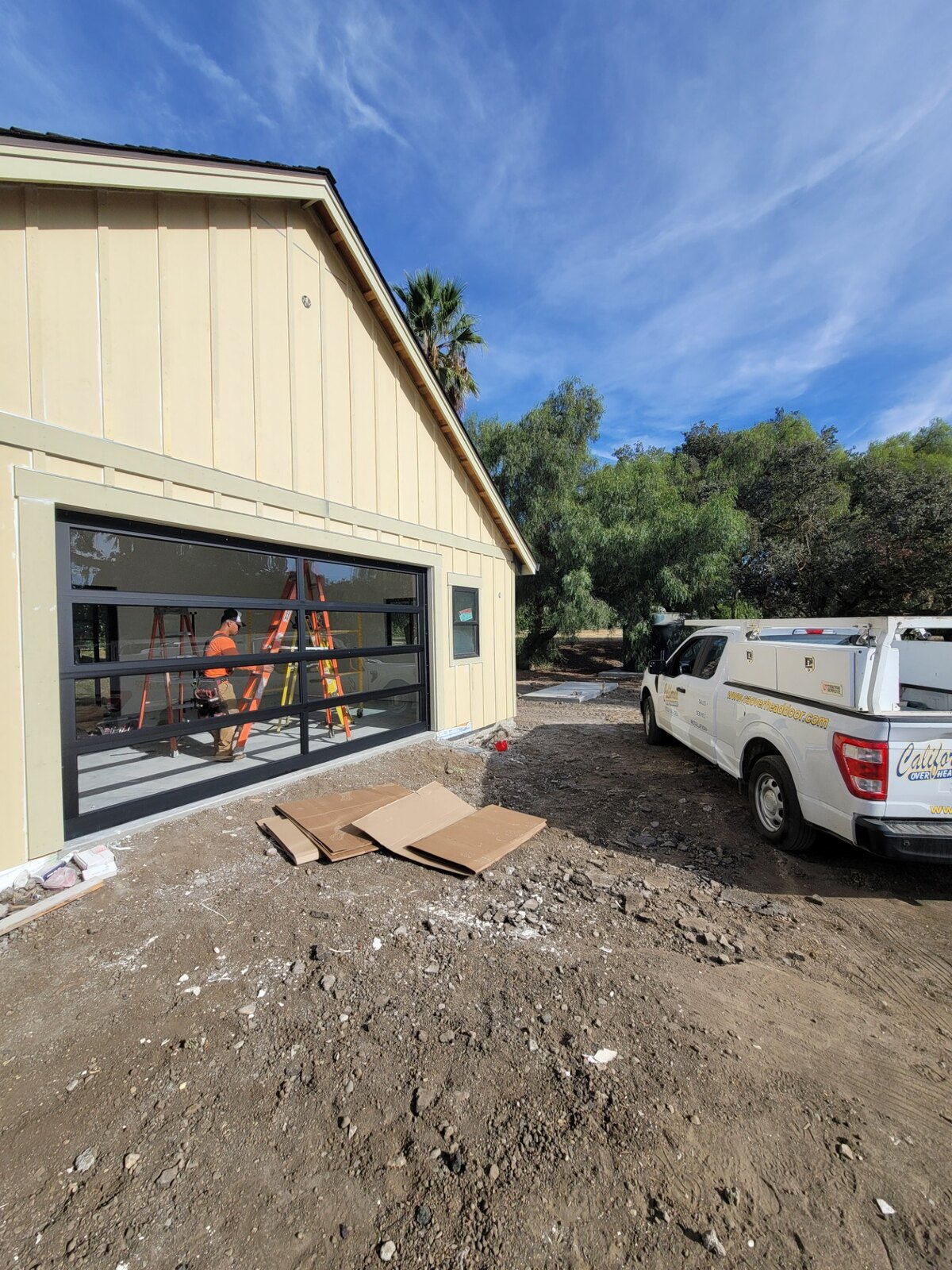 Wood-look garage doors on a modern farmhouse with service truck on site