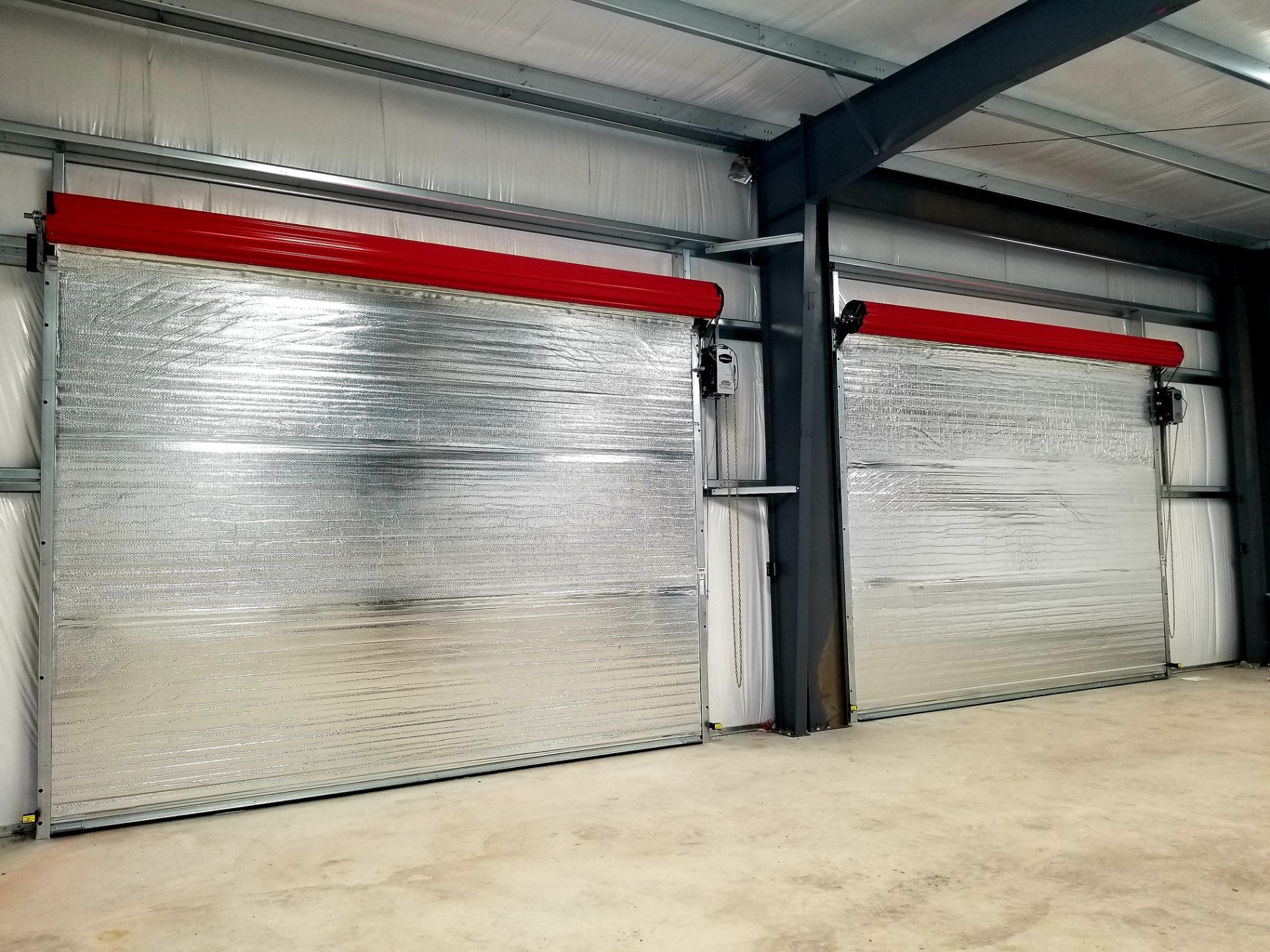 Commercial building with red roll-up service doors and security gate